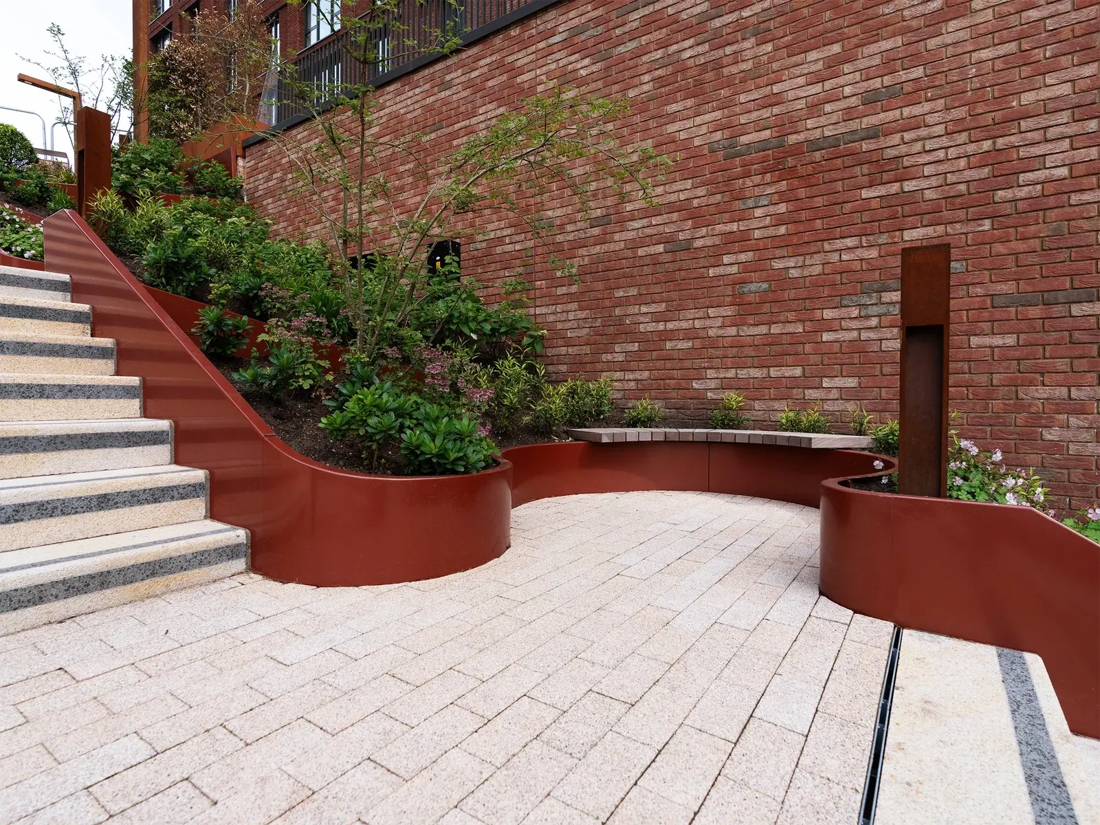 Curved metal planting edges around a paved resting area