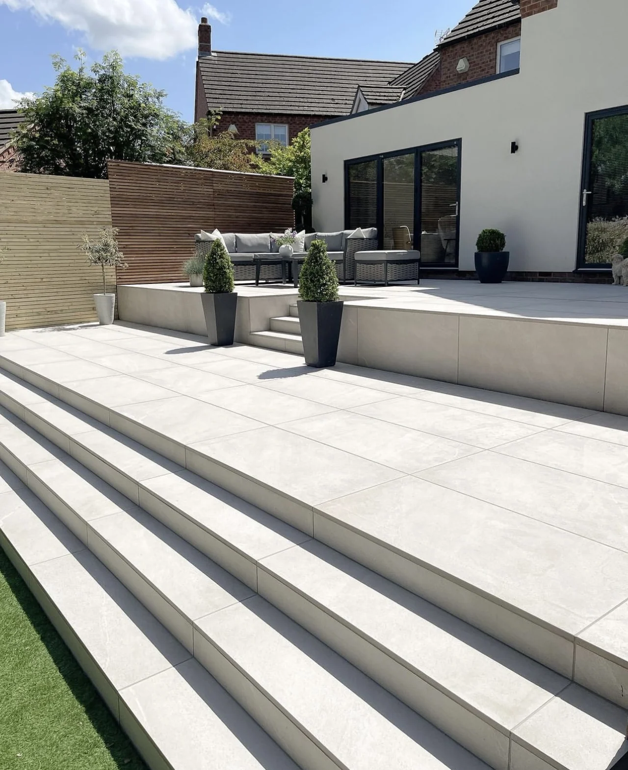 Chorus White paving and broad steps leading towards a house and garden seating