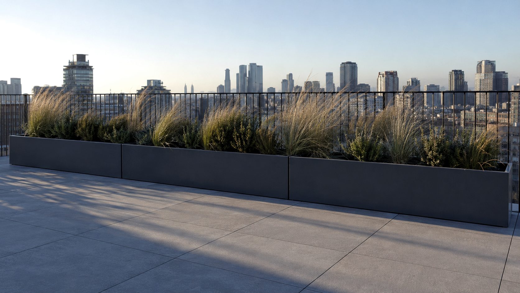 Illustration of three long dark grey planters with ornamental grasses along the edge of a paved roof terrace